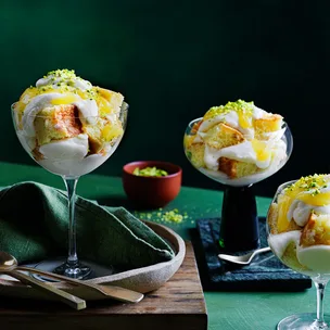 Three limoncello tiramisus in glasses on green benchtop.