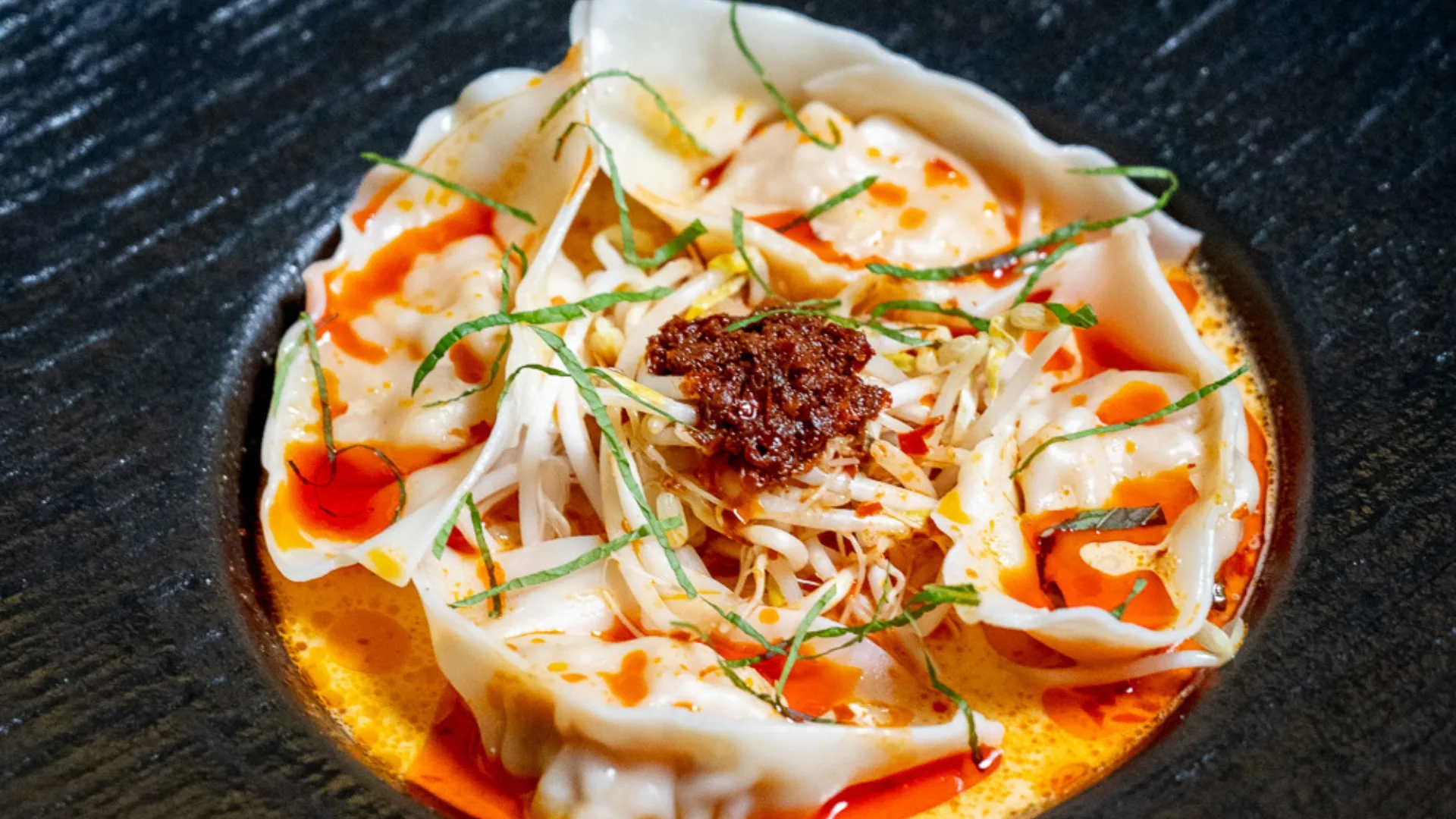 A close up picture of the laksa bombs at Ho Jiak Town Hall. Plump dumplings surrounded by a sea of coconut broth and sambal on top.