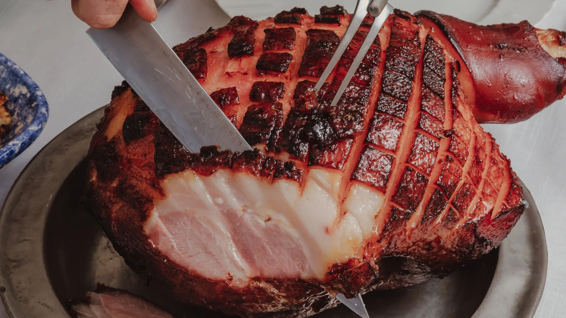 Picture of a ham being carved with sticky glaze and scored skin