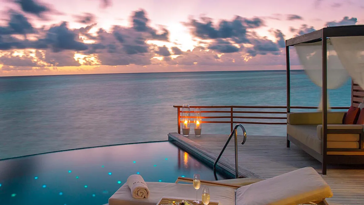 A beautiful evening sunset view from an overwater bungalow with infinity pool at Baros Maldives resort.