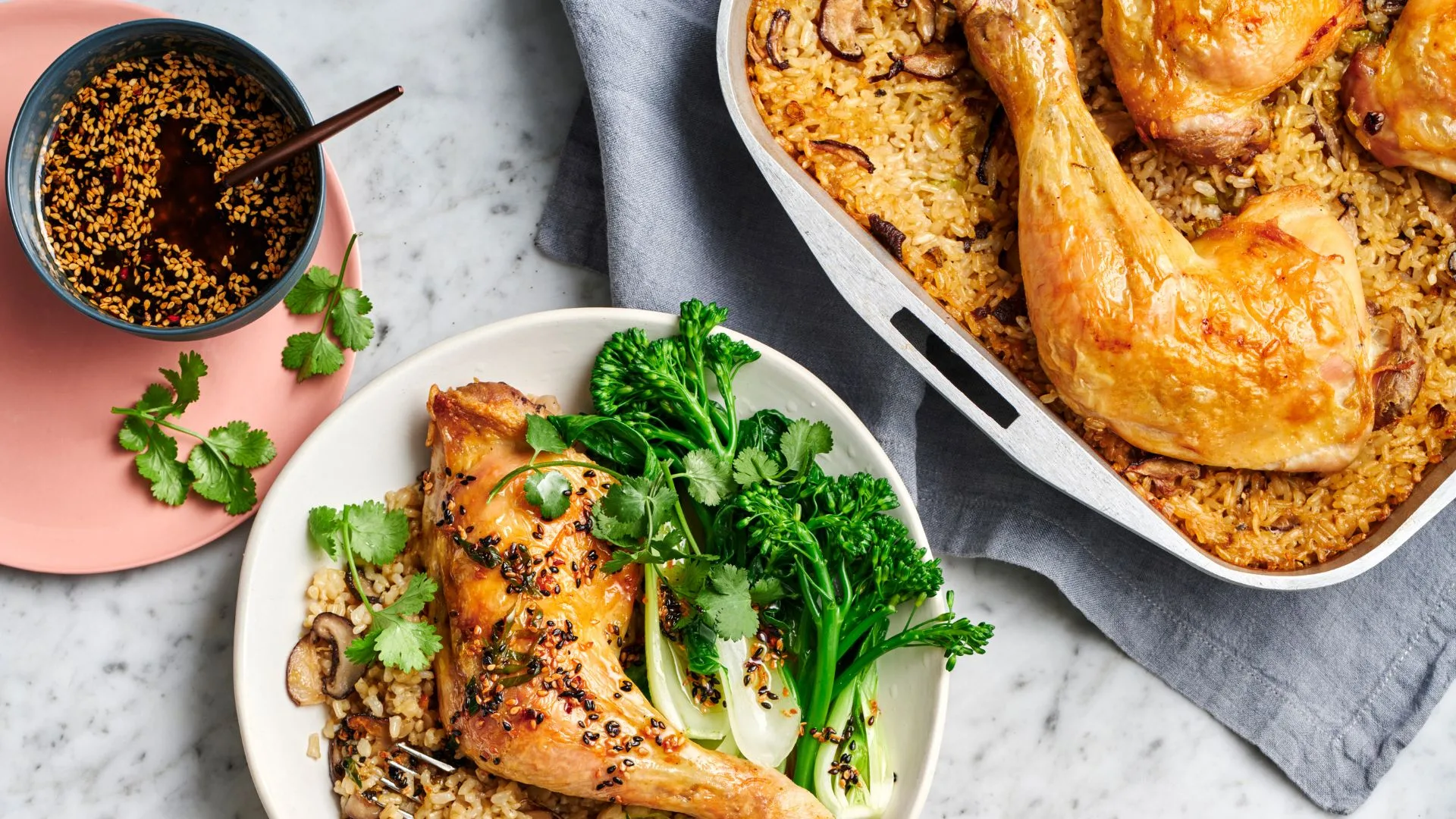 a chicken tray bake recipe in the pan alongside a plate serving of one chicken thigh and rice