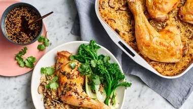 a chicken tray bake recipe in the pan alongside a plate serving of one chicken thigh and rice