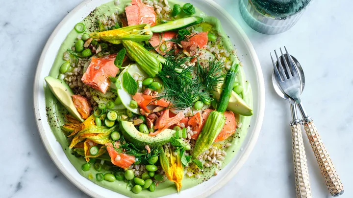 summer recipe dinner idea image of a colourful salad with green edamame beans, zucchini flower, herbs, avocado and pink ocean trout