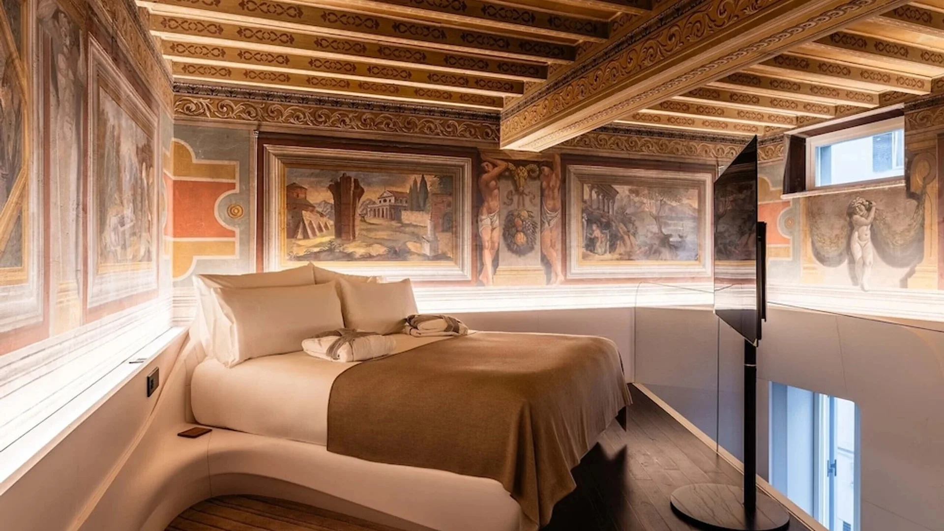 A suite at ROMEO Roma, decorated with Renaissance art paintings and a flat-screen television, makes it one of the best Rome hotels for luxury