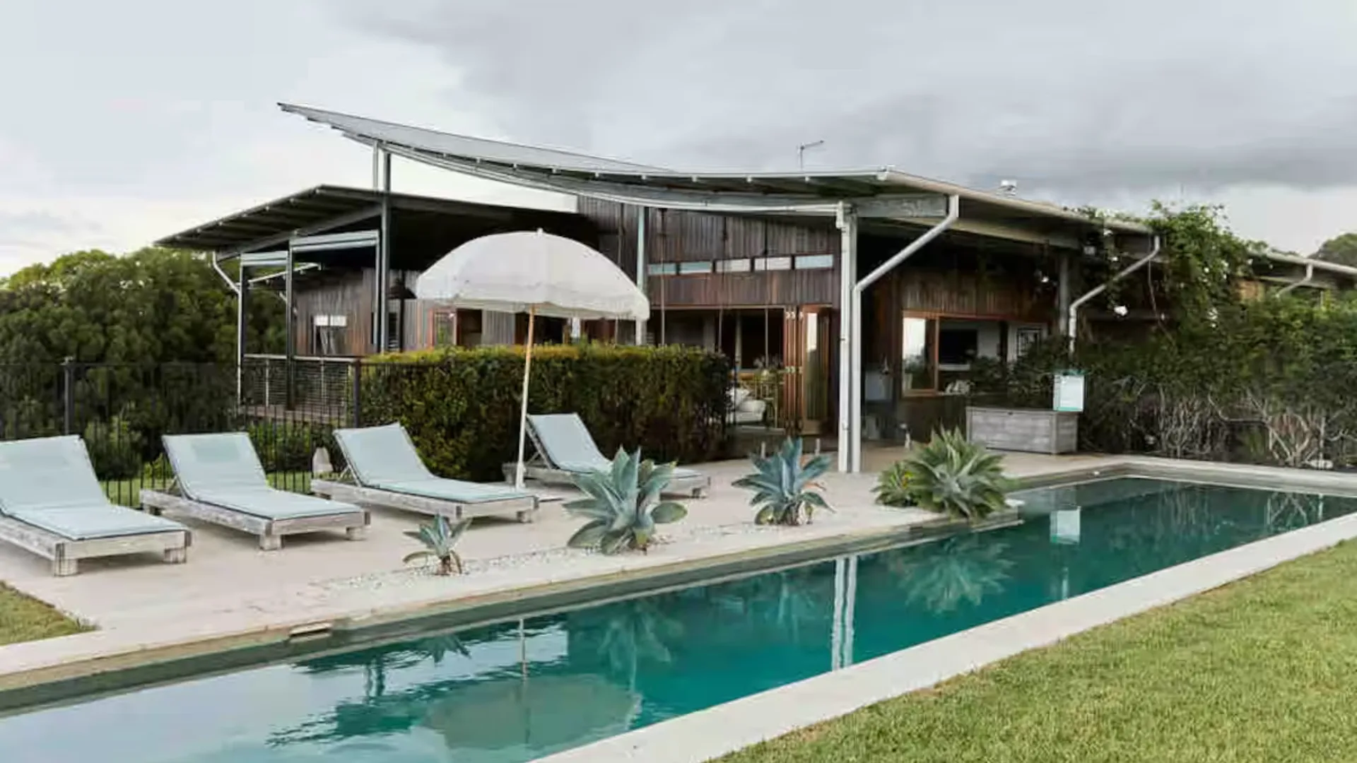 The pool and surrounding gardens at Temple Farmhouse, a luxe Airbnb stay in the Byron Bay hinterlands.