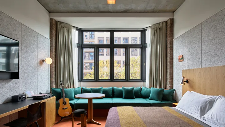 The large bedroom suite at Ace Hotel in Sydney has army blankets on the bed and an acoustic guitar.
