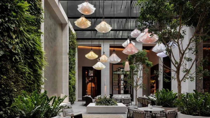 High ceilings and lush greenery in the atrium-style interior of Aperture Restaurant, Capella Sydney.