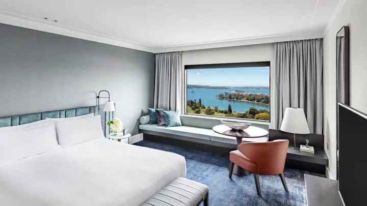 Crisp white bed with slate grey interiors in the corner king harbour room at the Intercontinental Sydney
