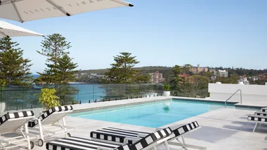 The blue rooftop pool with striped lounges at Manly Pacific