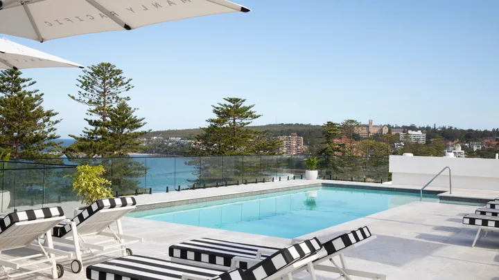 The blue rooftop pool with striped lounges at Manly Pacific