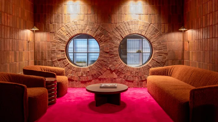 The plush red velvet and brick interior of the Guest Lounge at Hyde Melbourne Place