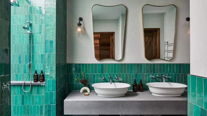 Green tiles, double sinks and mirrors, and elegant fittings in the Forest Lodge bathroom at Osborn House.