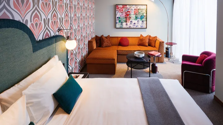 The Groovy Suite bedroom with rust-coloured sofa and bright decor at Ovolo South Yarra.
