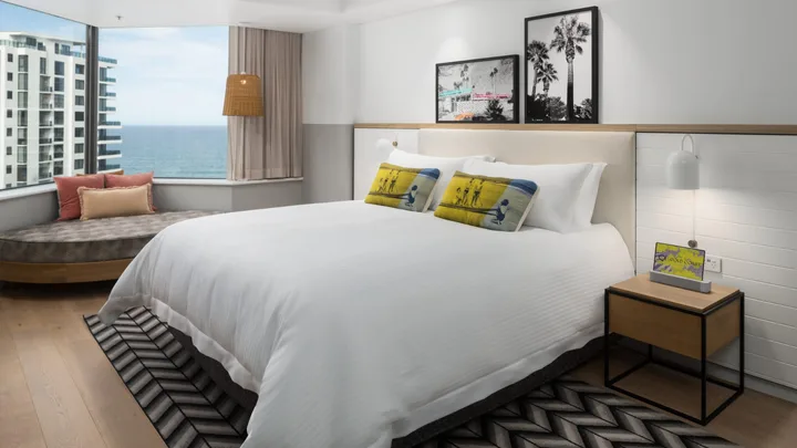 The King Suite Ocean View bedroom with crisp white interiors with yellow pops of colour at QT Gold Coast