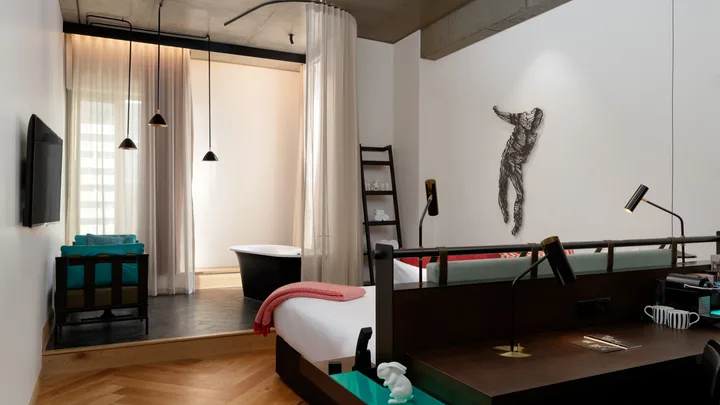 The spacious and industrial-style Corner King Suite with freestanding bathtub at QT Melbourne
