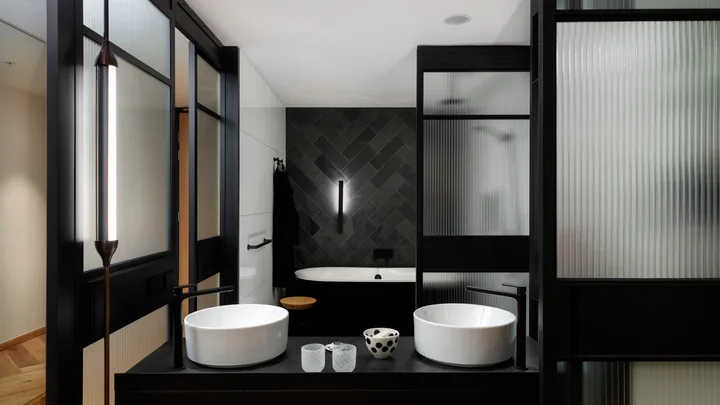 The dark, chic interiors of the Executive King Bathroom with panelled glass at QT Melbourne