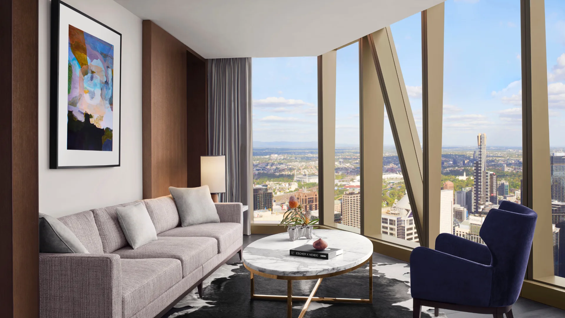 The elegant grey, blue and wood tones of the Executive Suite Living Room with floor to ceiling windows at The Ritz-Carlton Melbourne