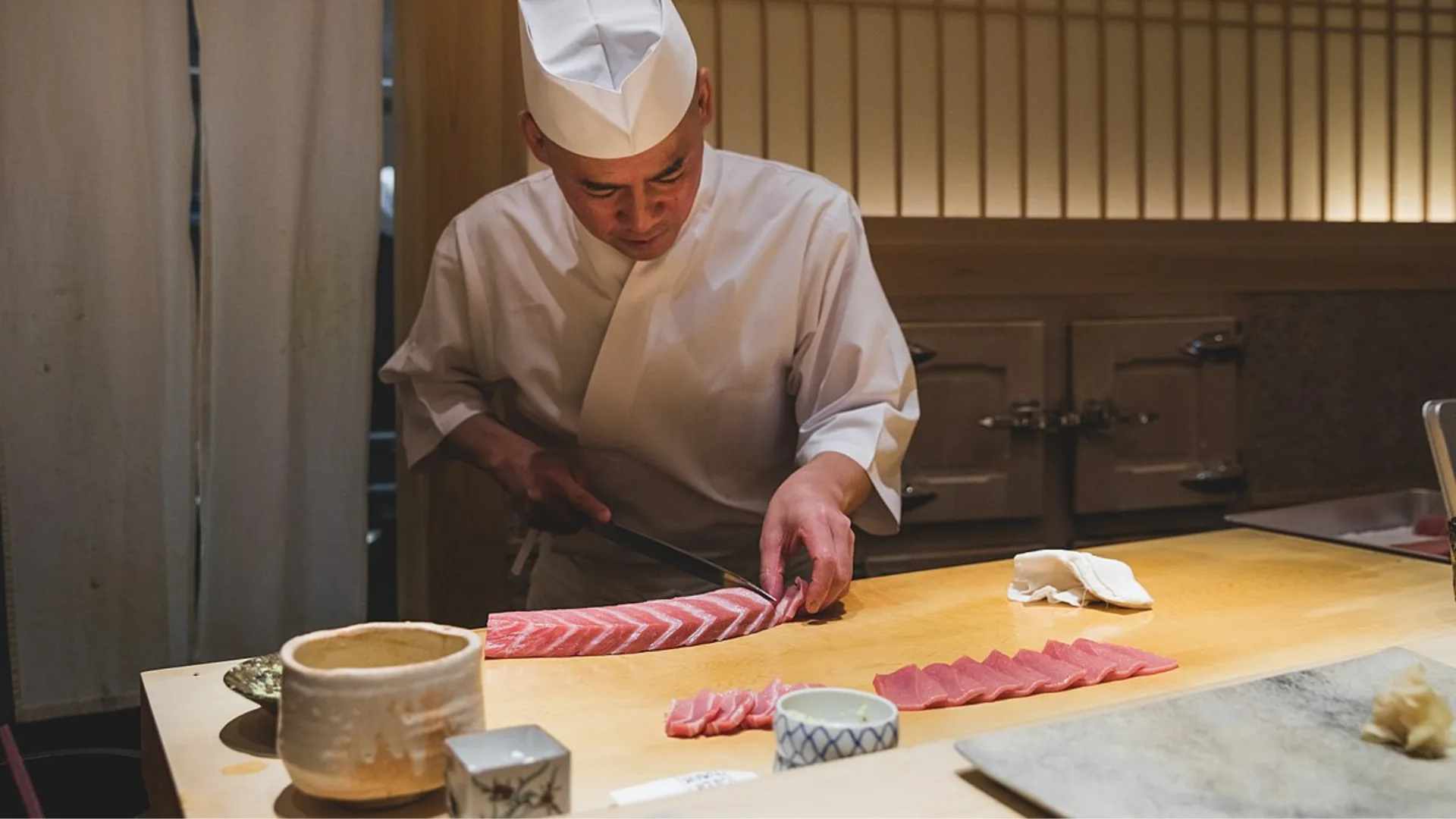 One of the chefs at Sushi Saito cutting sashimi.