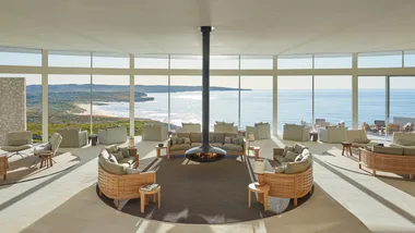 The Great Room at Southern Ocean Lodge features a cosy fireplace and floor to ceiling windows with ocean views