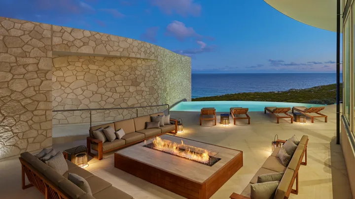 A fire pit and seating area by the pool at night at Southern Ocean Lodge