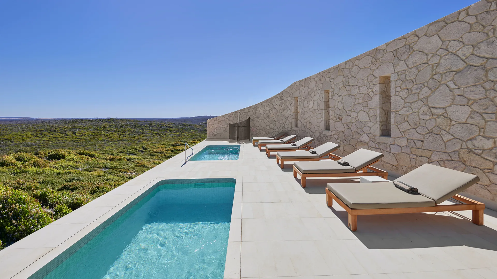 Sun loungers and a pool terrace at the spa at Southern Ocean Lodge