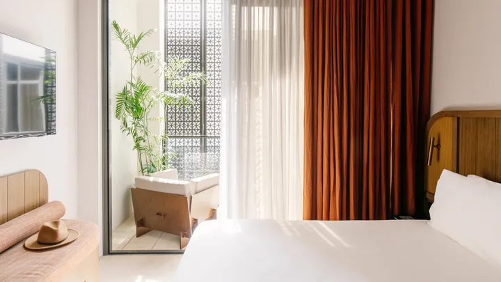 Soft whites and burnt orange drapes in the bedroom suite at Basq House in Byron Bay.