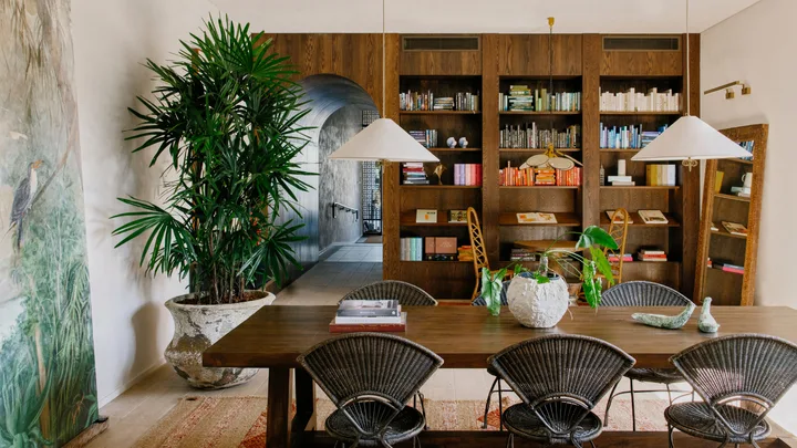 The library at Basq House in Byron Bay with wooden shelving and lots of greenery,