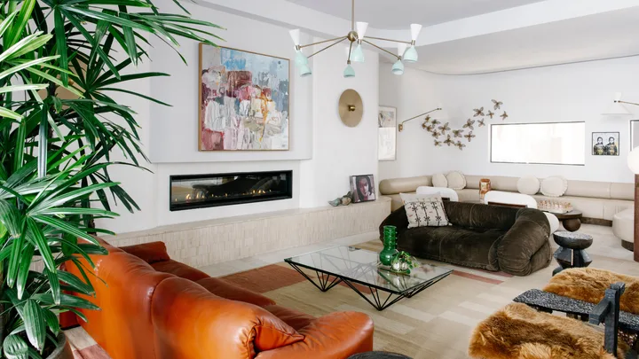The shared lounge with faux fireplace and tan armchairs at Basq House in Byron Bay.