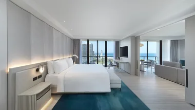 Crisp white bed linen and a plush blue rug in the spacious Executive Suite bedroom at JW Marriott Resort & Spa.