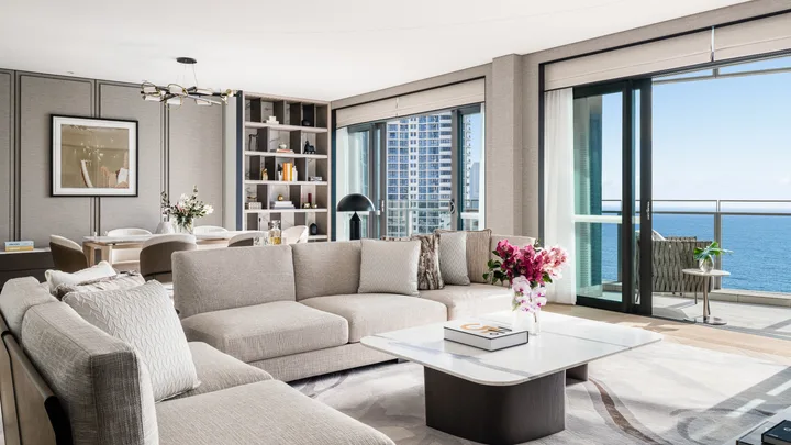 The spacious living area of the Presidential Ocean Suite with crisp white decor and floor to ceiling windows with ocean views at Langham Gold Coast.