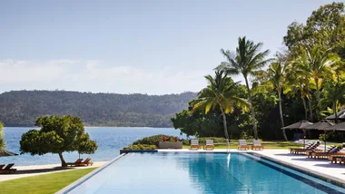 The stunning outdoor pool is lined with palm trees and overlooks the ocean at Qualia