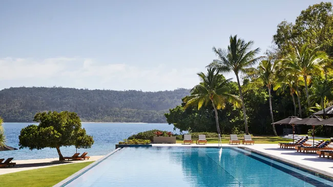 The stunning outdoor pool is lined with palm trees and overlooks the ocean at Qualia