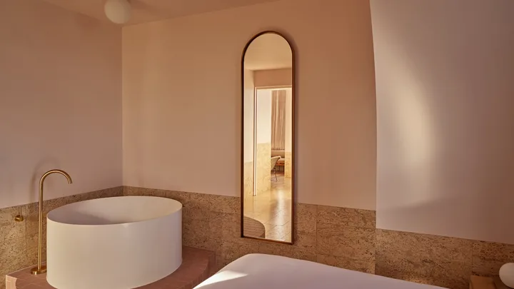 The bathroom with deep freestanding round bathtub and arched, full-length mirror at The Calile, Brisbane.