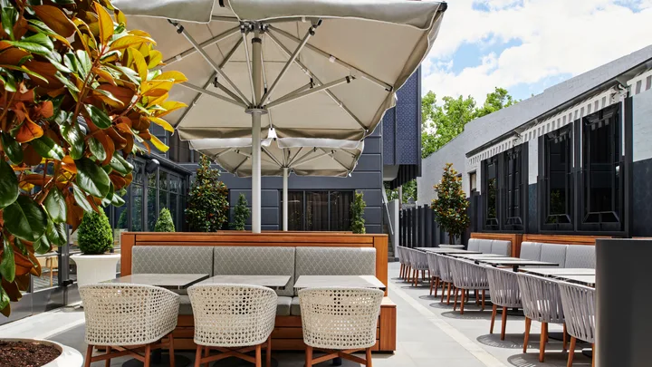 The sun-drenched Conservatory with umbrellas and green foliage at the Royce Hotel, St Kilda
