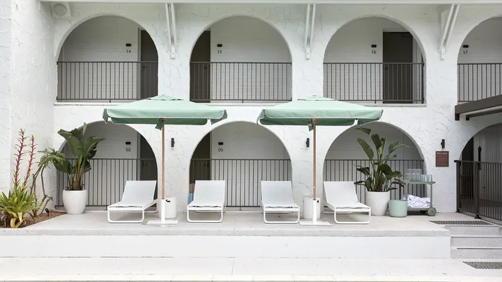 The pool terrace with olive umbrellas and white sun lounges at The Tamborine, Queensland