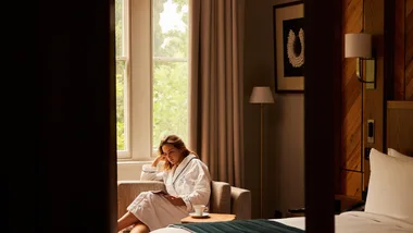 A woman sits in the window at the bedroom of the St Davids Park Suite at The Tasman Hotel.