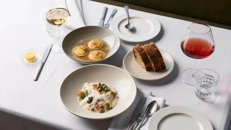 A spread of dishes and wine on a white tablecloth at Melbourne restaurant Harriott