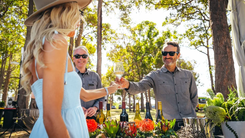 The Pair'd Grand Tasting presented by Singapore Airlines. Female beinghanded a glass of wine in an outdoor setting