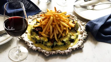 A photograph of Loulou's platter of steak frites with a rich, creamy sauce.