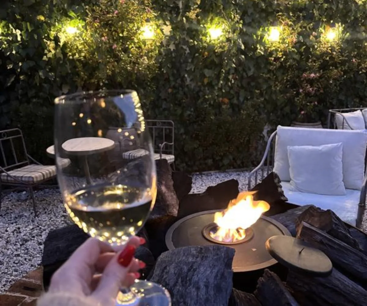 Holding a glass of wine, sitting in front of a fire pit