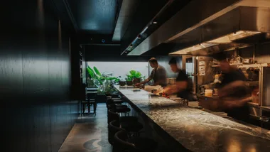 Chefs behind the pass in the moody interior of Brisbane restaurant Essa