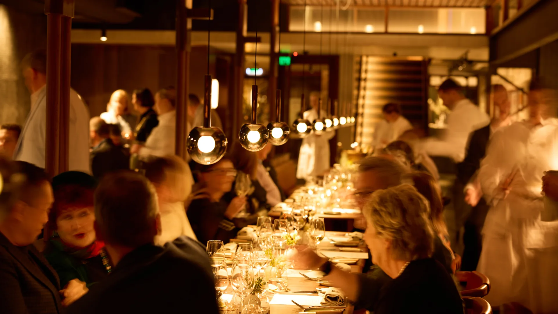 Guests at a long table enjoying dinner under warm, glowing lights at Winnifred's in Brisbane.