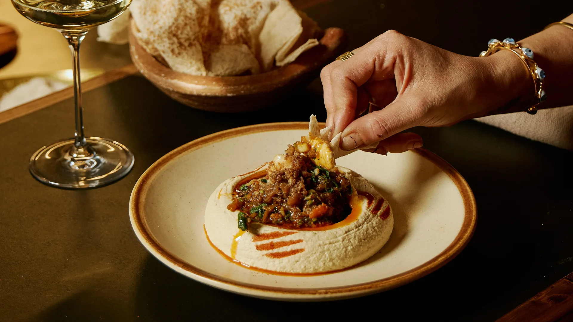 Swiping bread through hummus topped with prawn and crab at Melbourne restaurant Zareh.