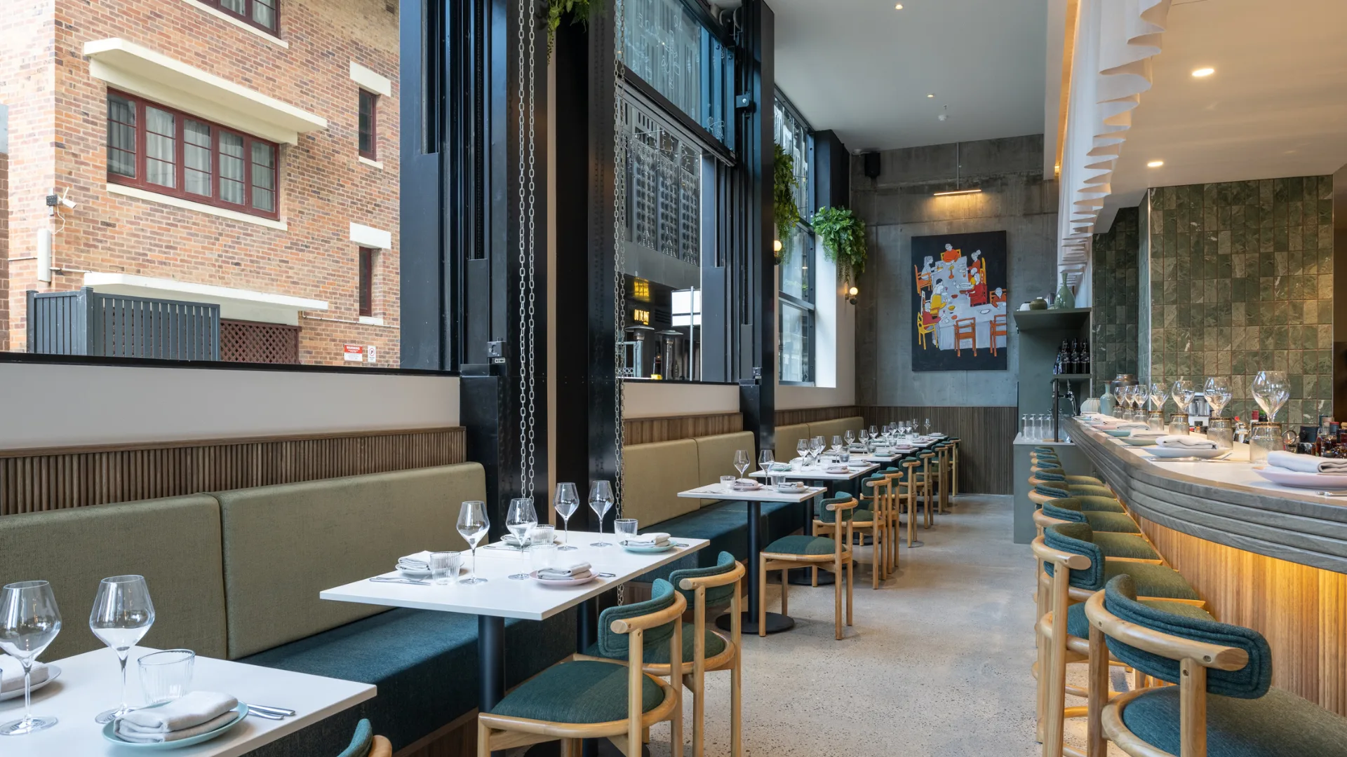 The interior of South Brisbane bistro Clarence, with soft green fabrics, a curved bar, and bold artwork.