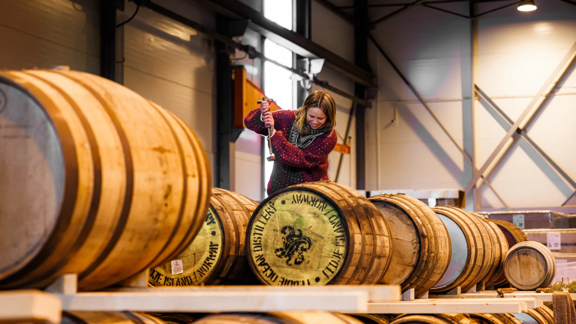 A woman working in a distillery filled with barrels