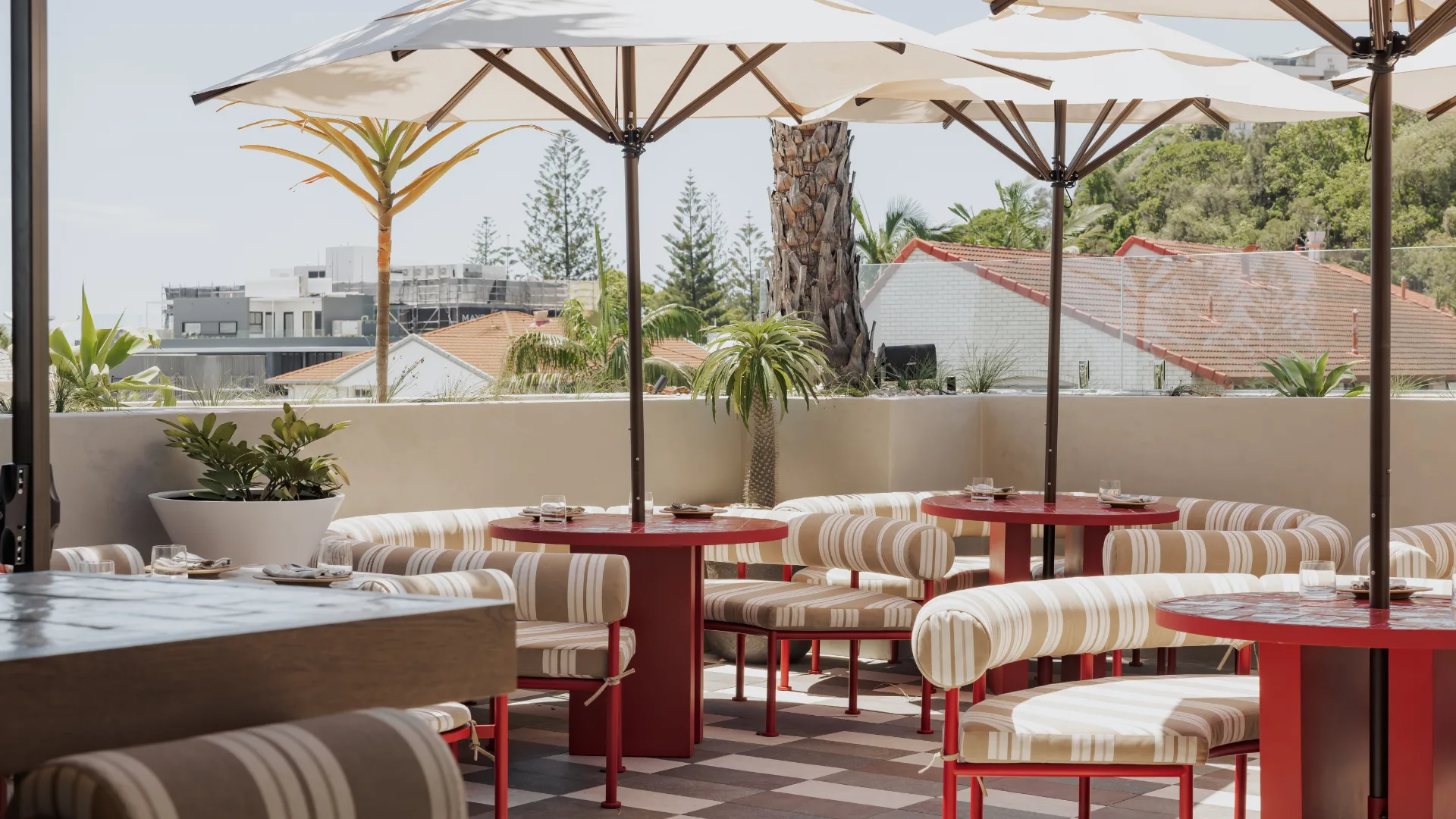 The outdoor bar area with white umbrellas and red furniture at Sueno on the Gold Coast.