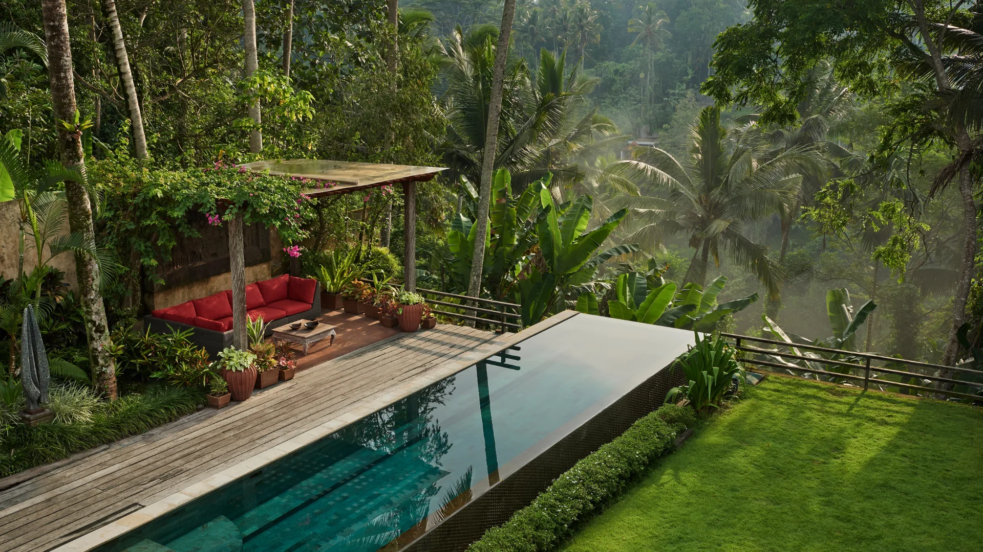 Garden and pool area of private villa, resort situated in Ubud, with mist rising up from valley at dawn