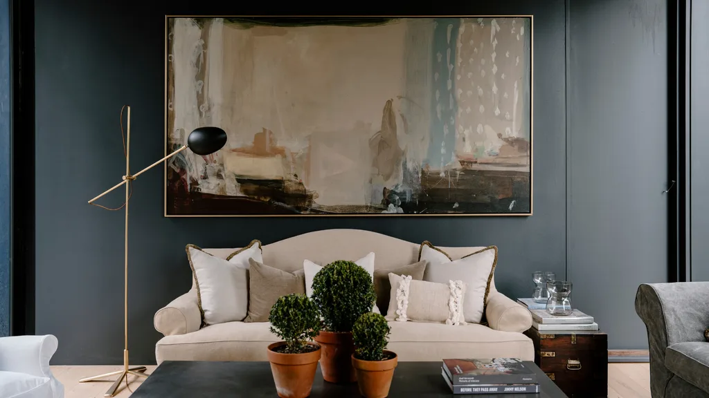 Cream sofa with blue walls and painting behind it