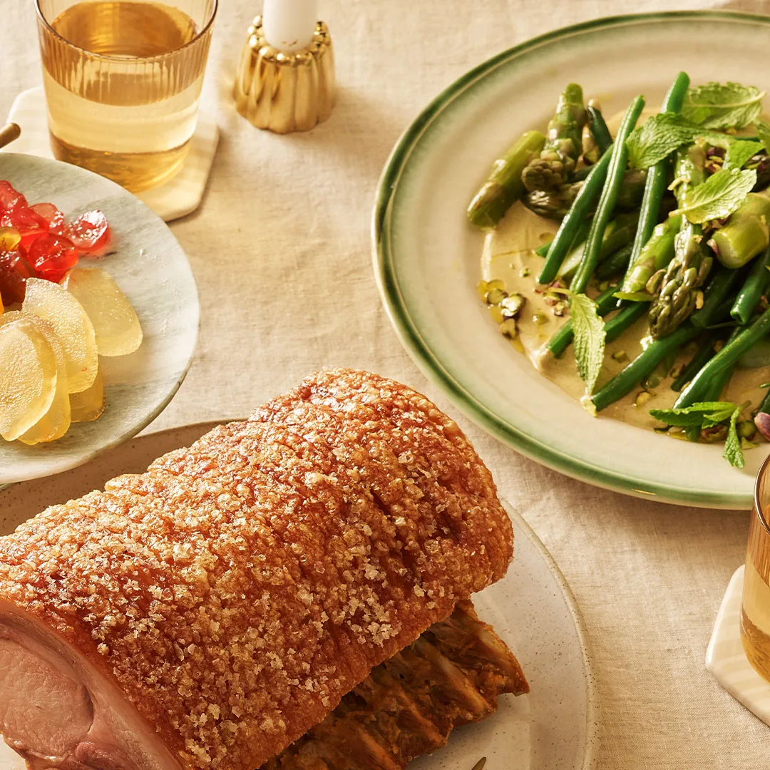 A picture of crackling pork and a side salad of asparagus, green beans and pistachio.