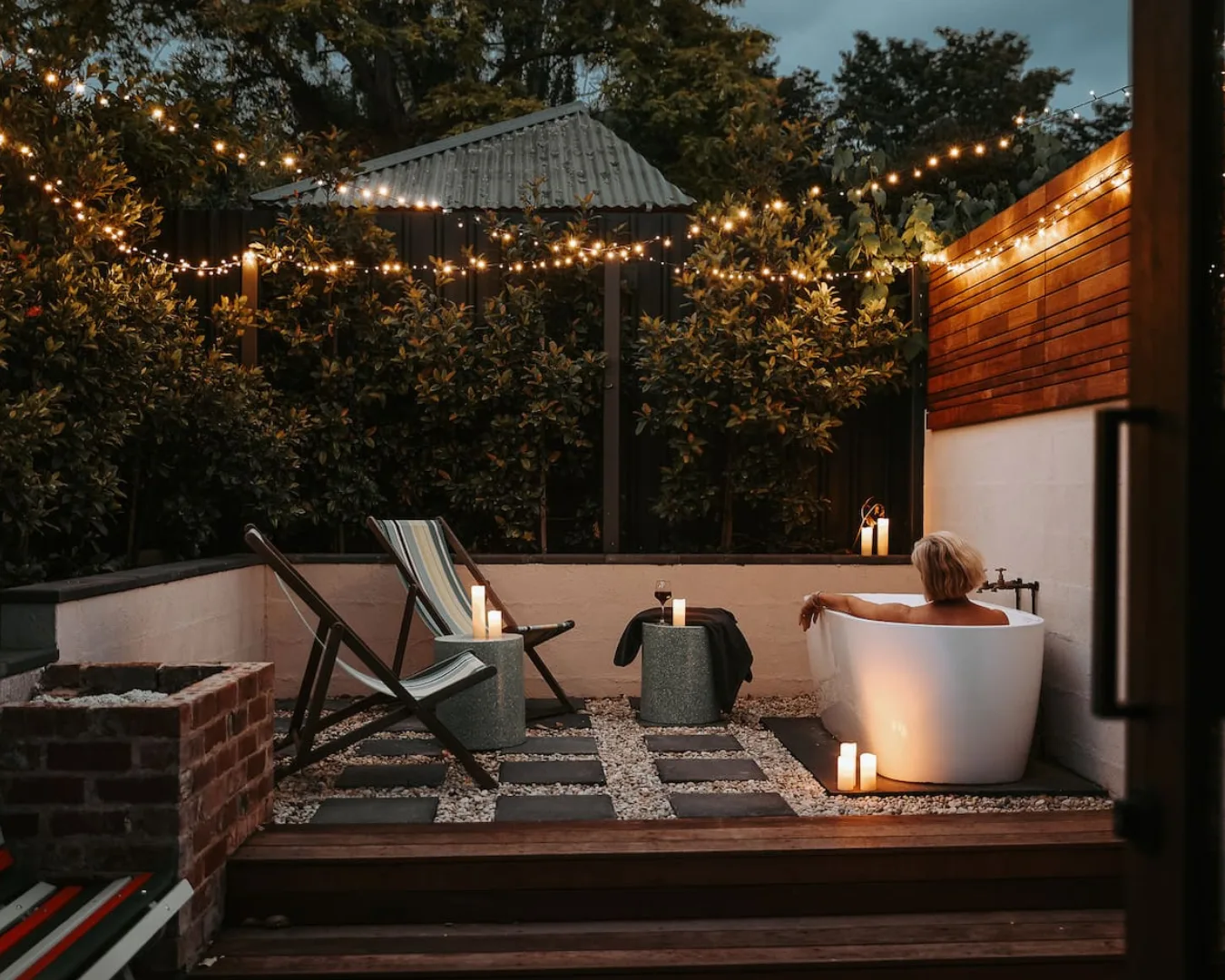 Enjoying an outdoor bath with fairy lights in the courtyard of Hobart Airbnb Braithwaite.